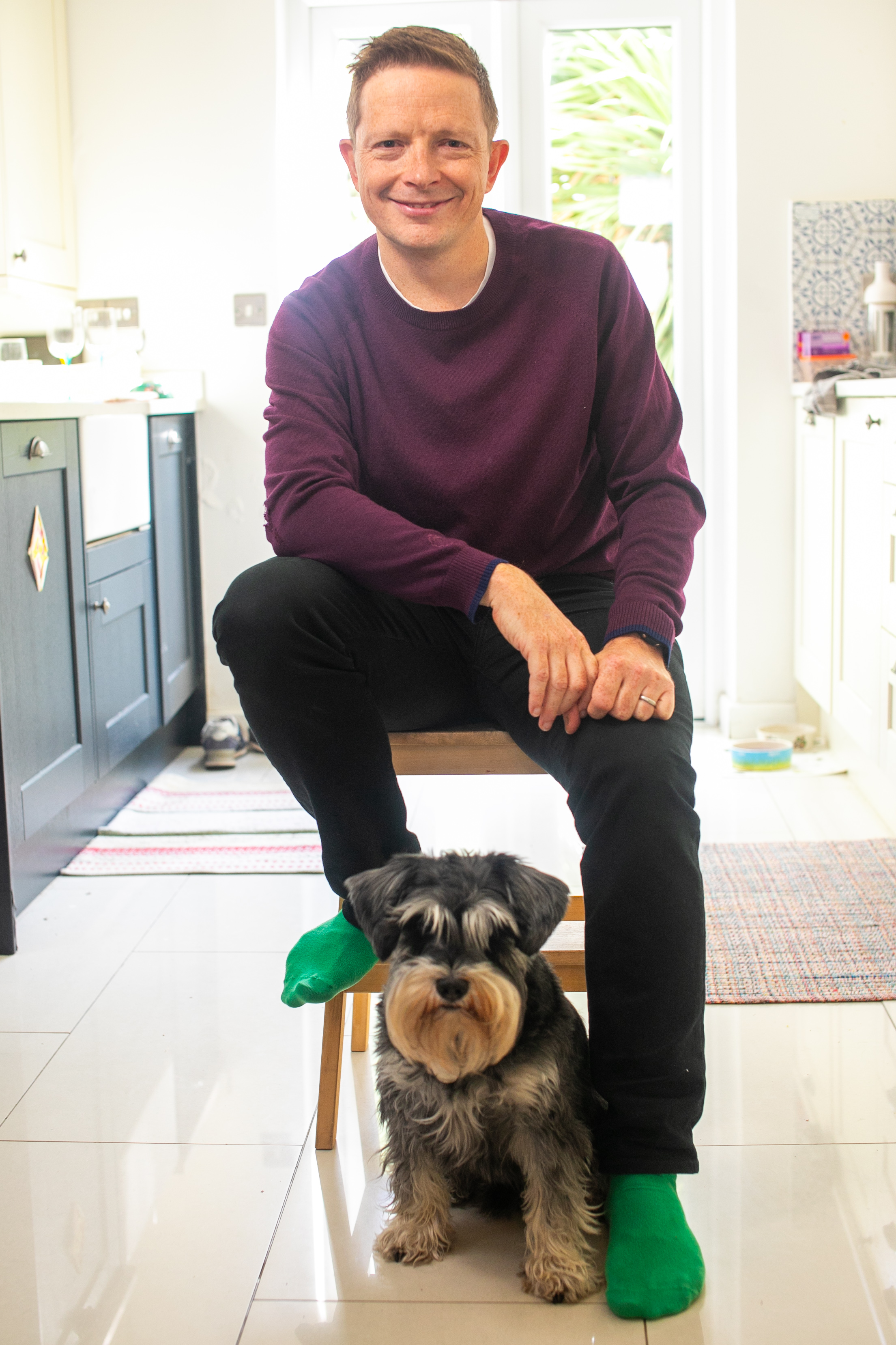 Photograph of HSF Kramer Alumnus Oliver Elgie and his dog, a Miniature Schnauzer at home in his kitchen